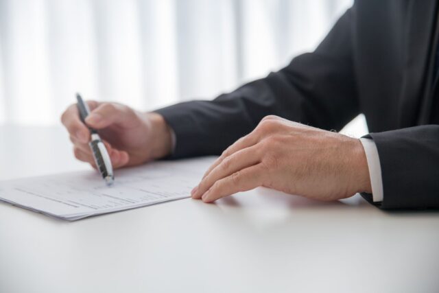 Semnarea unui antecontract imobiliar cu stiloul, pe o masă de birou, alături de documente