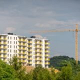 Persoană care citește anunțuri imobiliare pe laptop, cu un carnet de notițe alături