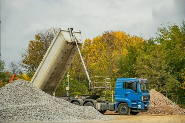 Paleți cu saci și plăci descărcați lângă intrarea unui bloc, pregătiți pentru o renovare